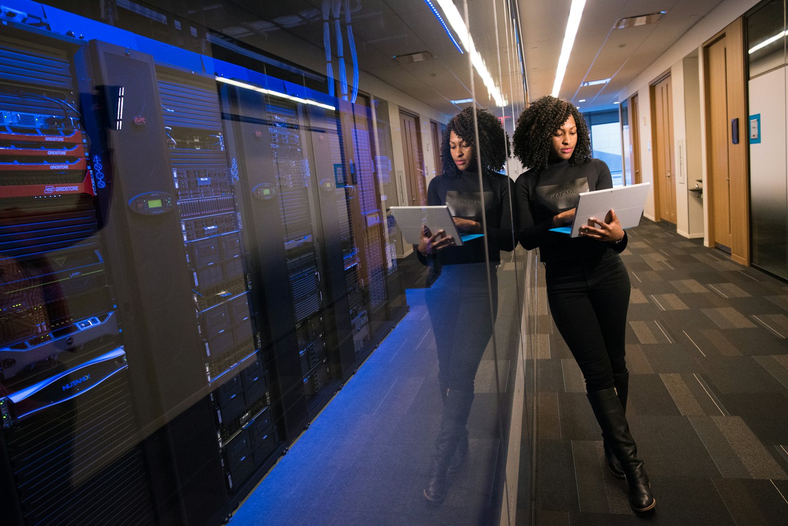 Two engineers with laptops in a data-centre aisle lined with server racks